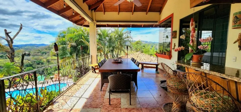 Tropical veranda with dining table and lush view.