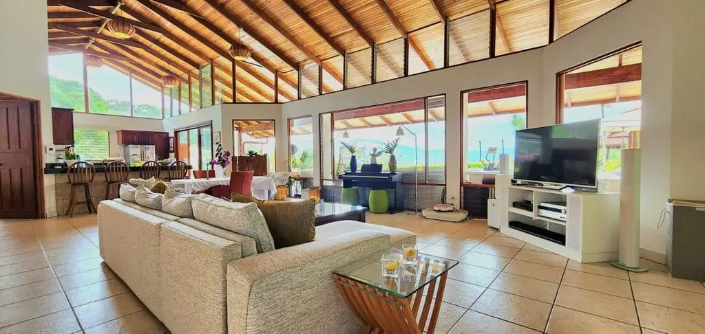 Spacious living room with large windows and TV.