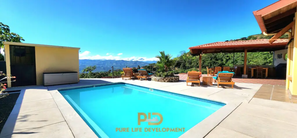 Outdoor pool with mountain views and seating area.