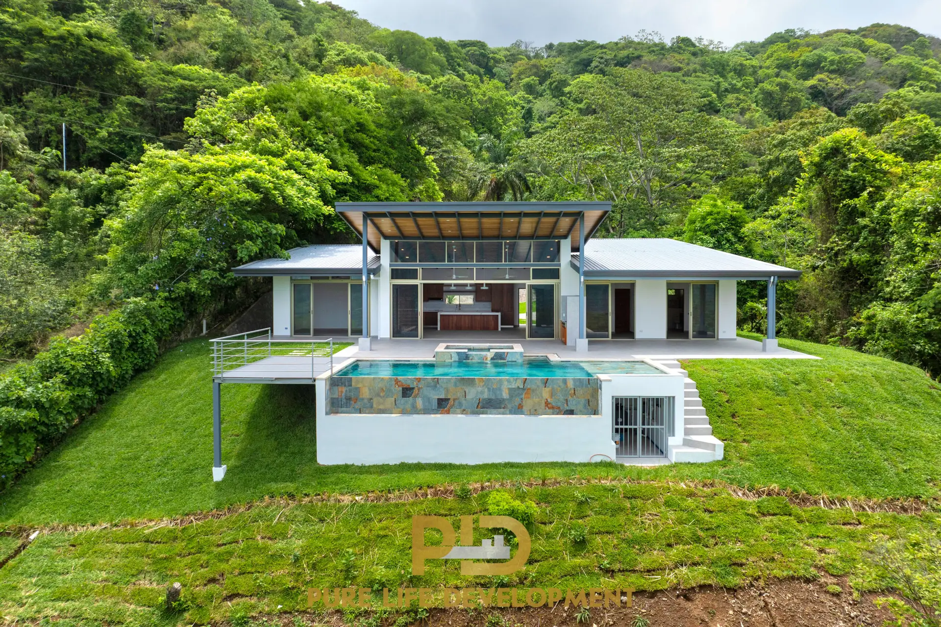 Exterior view of a modern 3-bedroom home in Atenas, Costa Rica, featuring a private pool, landscaped grounds, and guest house in a gated community.