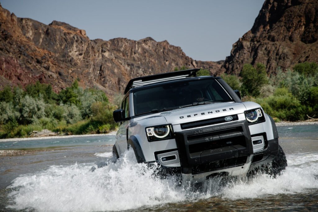 SUV crossing a river in rugged terrain.