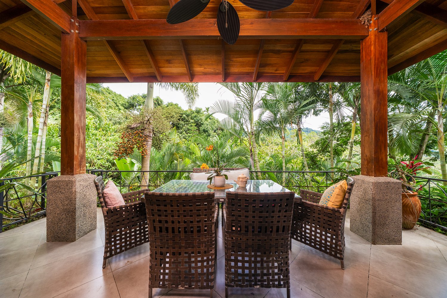 Tropical outdoor patio with wooden ceiling and lush greenery.