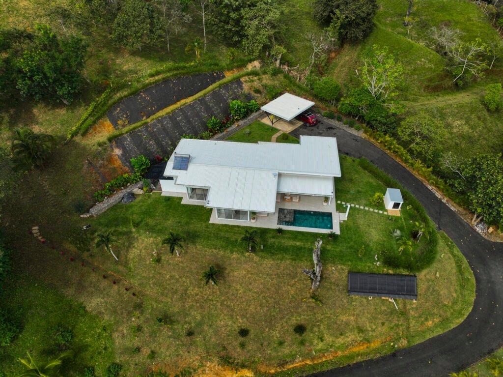Aerial view of modern house with pool in greenery.