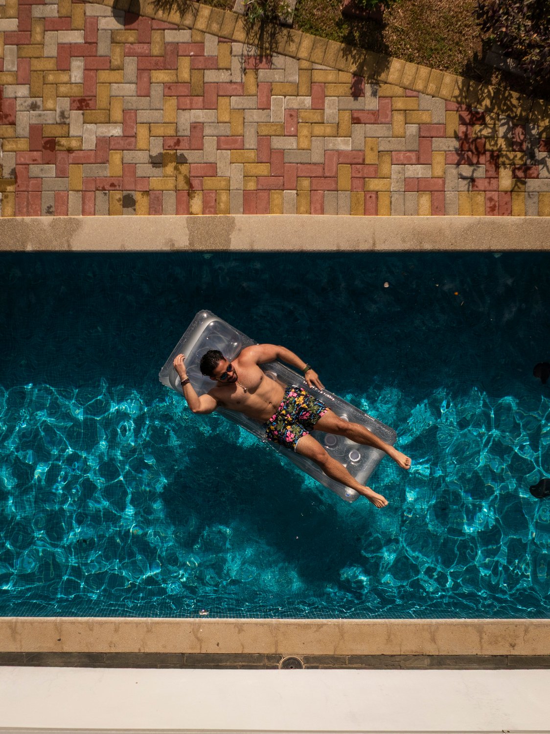 Man relaxing on pool float in sunny weather.