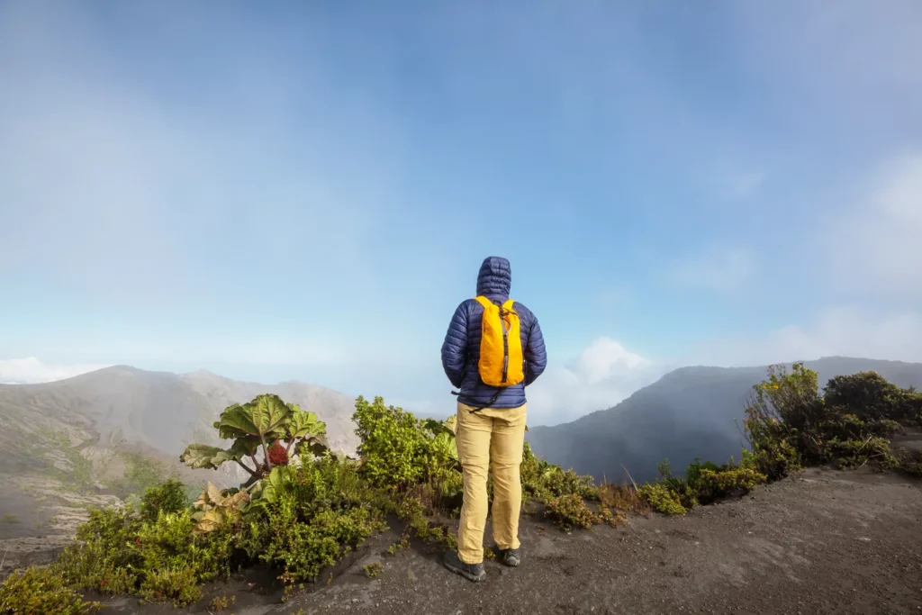 Hiker with backpack overlooking mountain landscape.