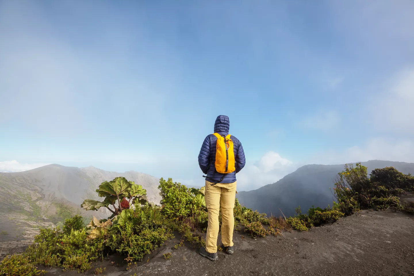 Hiker with backpack overlooking mountain landscape.