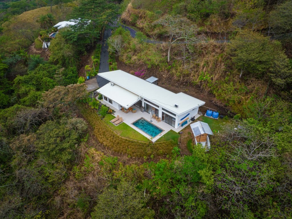 Aerial view of modern hillside home with pool