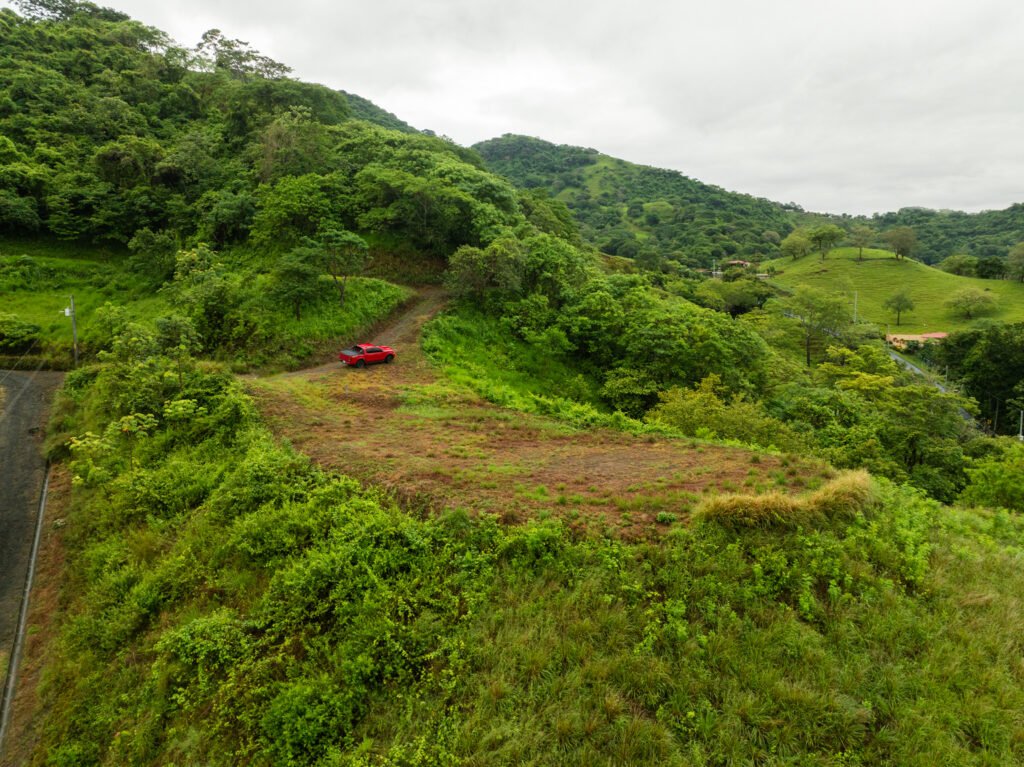 Red pickup on lush green hillside trail