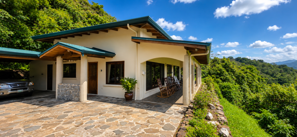 Tropical hillside home with covered porch and rocking chairs
