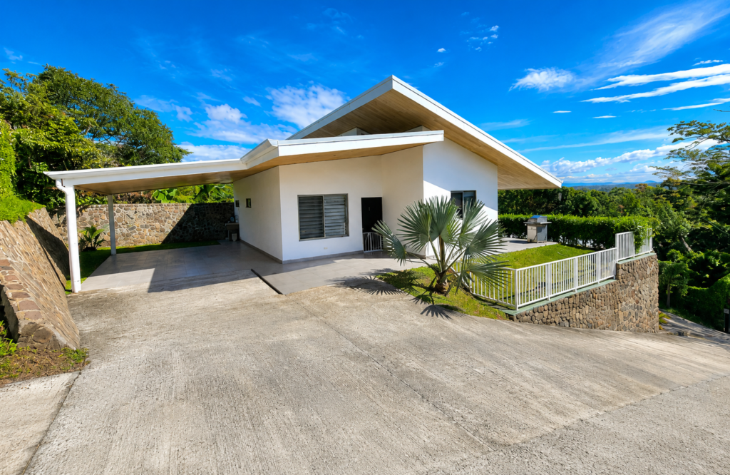 Modern hillside home with carport and tropical landscaping