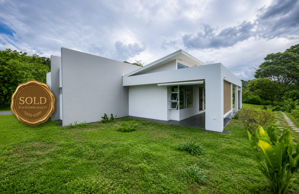 Modern white home with lawn and sold badge