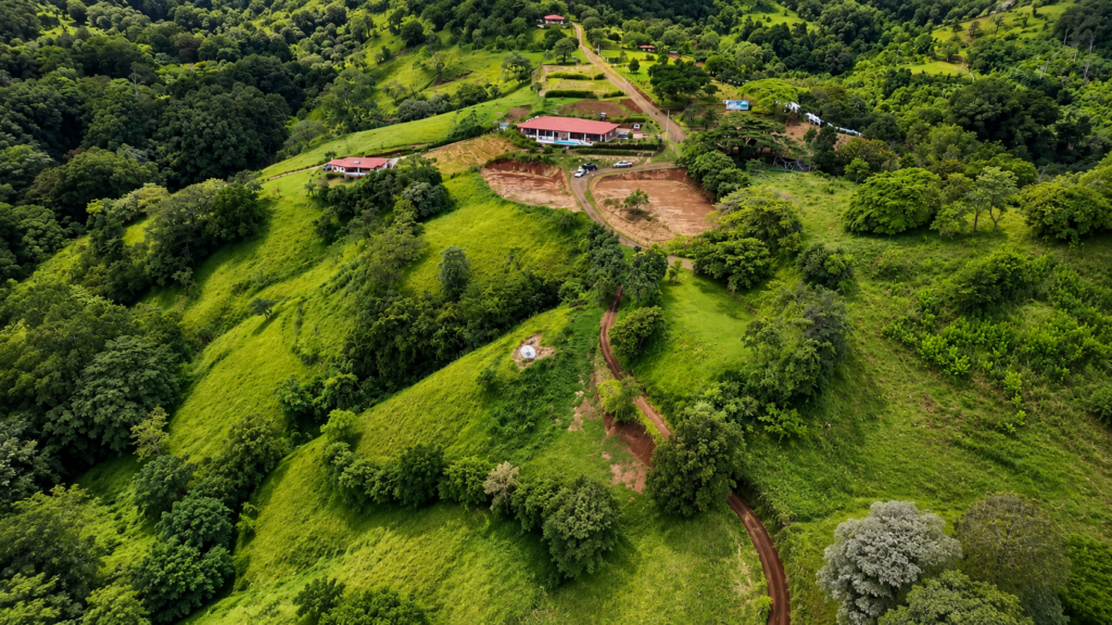 Aerial view of lush green hills and farmhouse