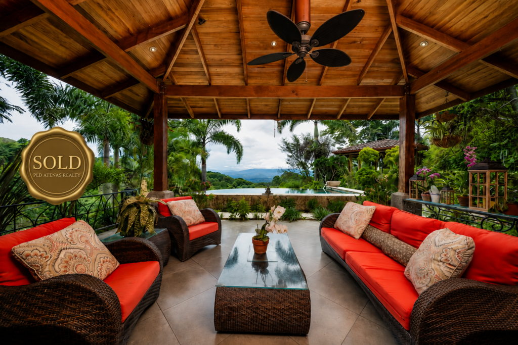 Covered tropical patio with red sofas and view