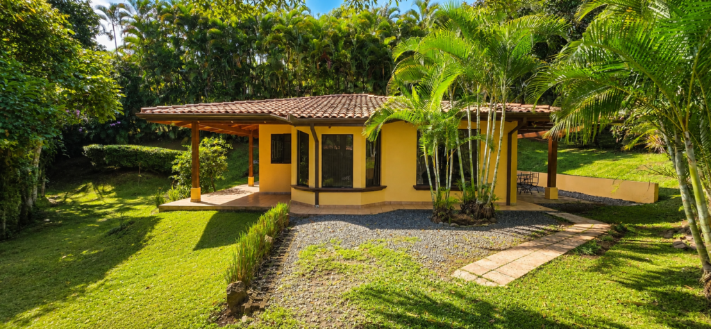 Yellow tropical cottage surrounded by palms and lush garden