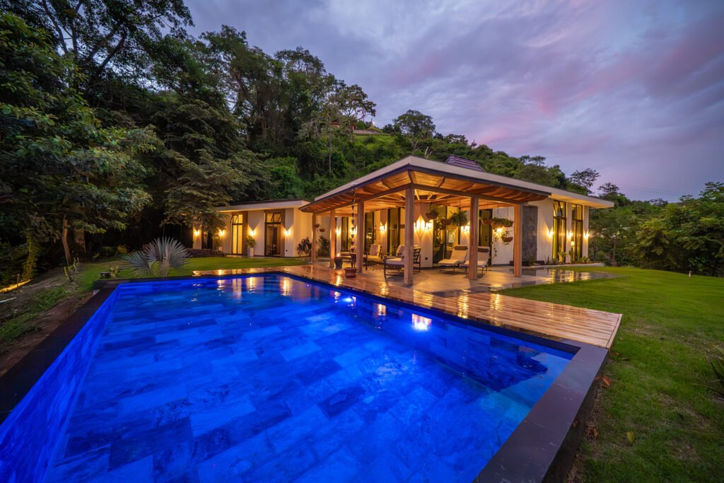 Modern tropical villa with illuminated pool at dusk